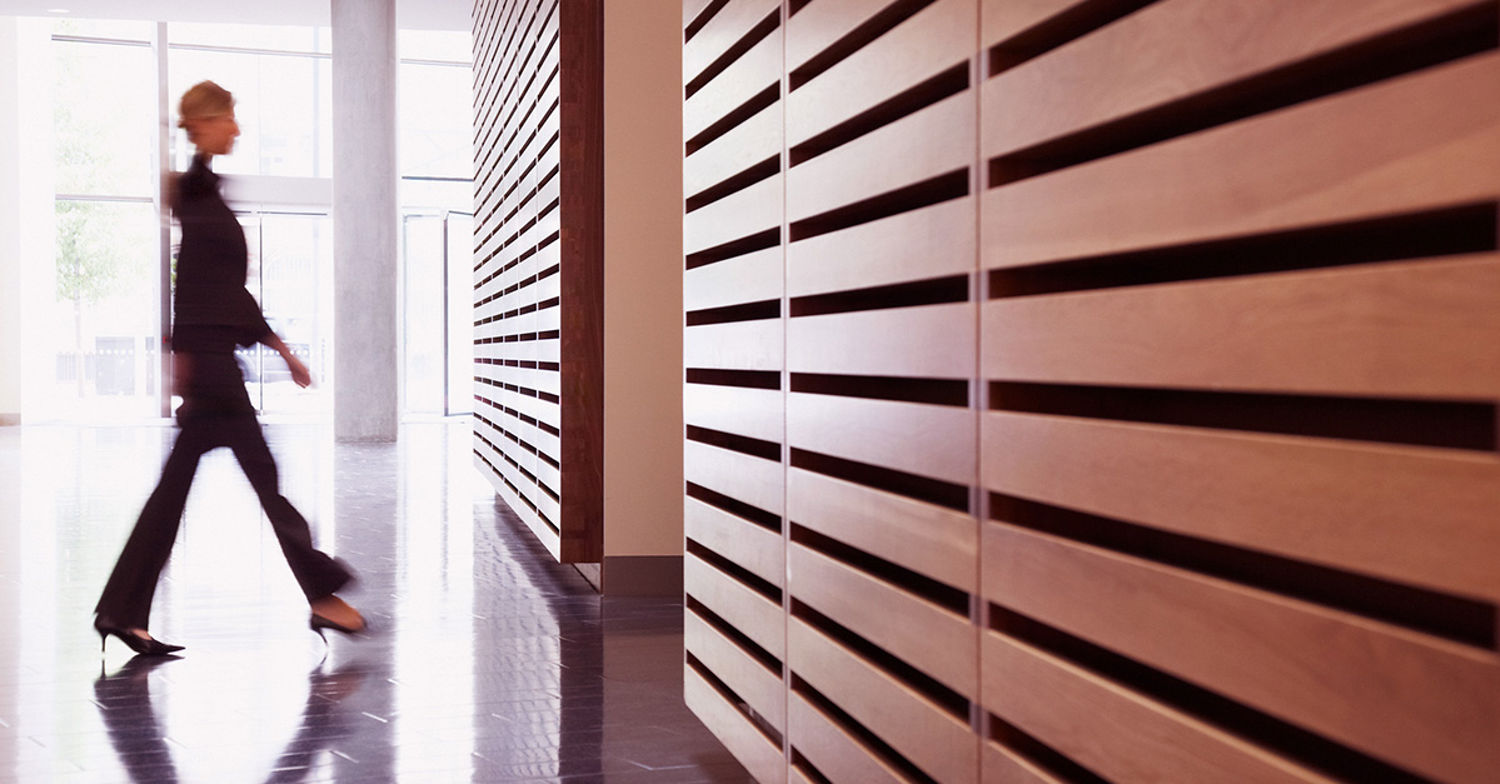 Kvinna går i korridor med träpaneler på väggen.
