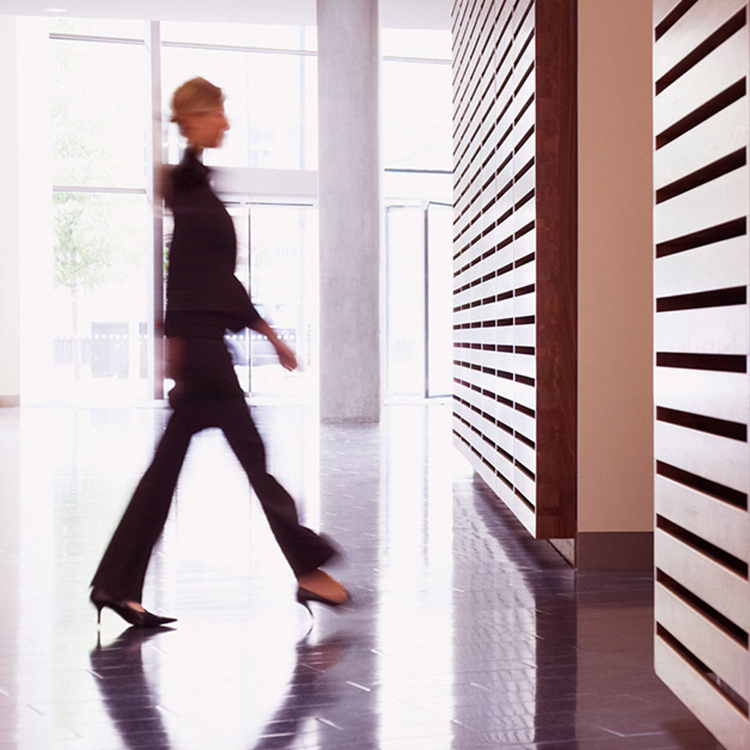 Kvinna går i korridor med träpaneler på väggen.