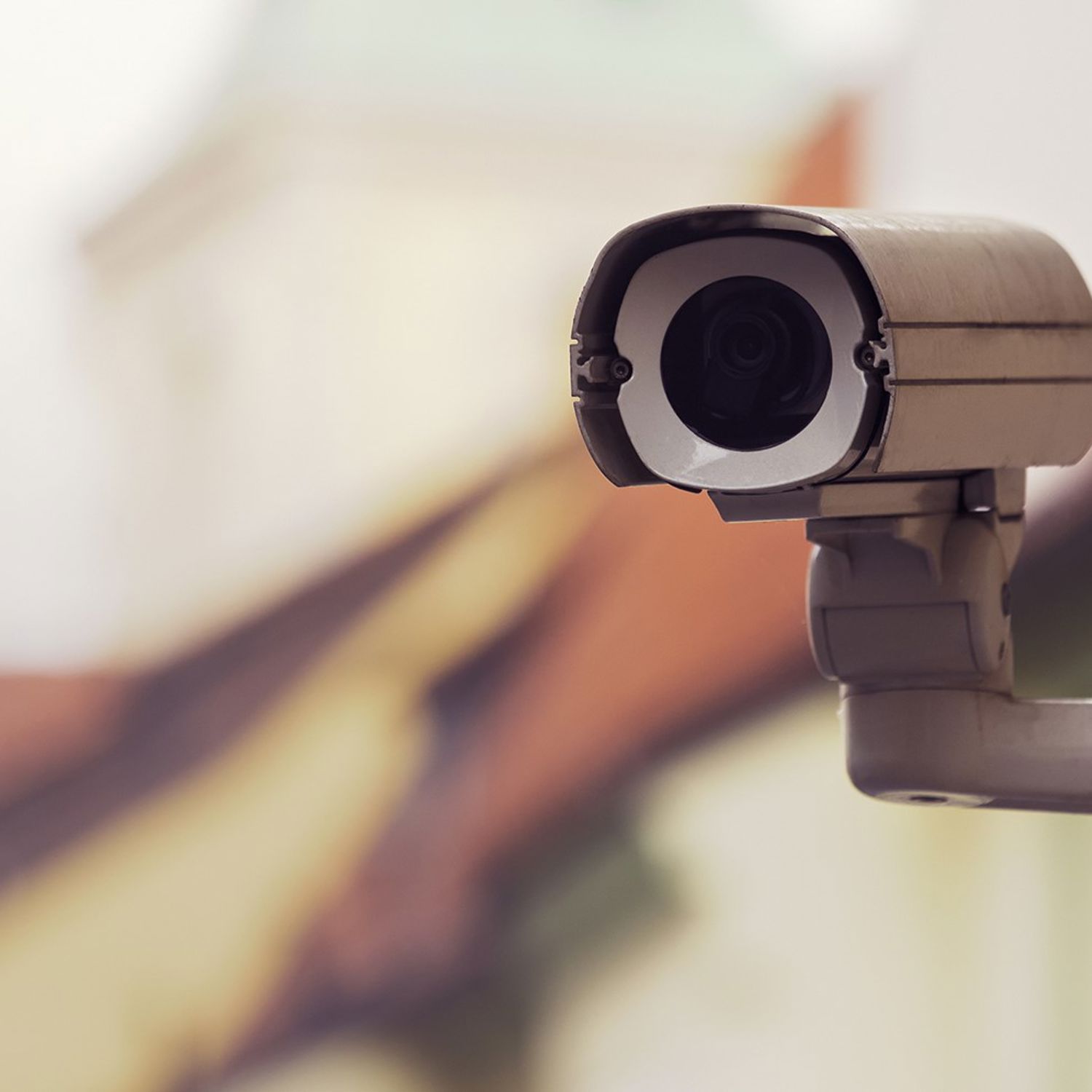 En kamera som är monterad på en gul fasad till ett lägenhetshus.