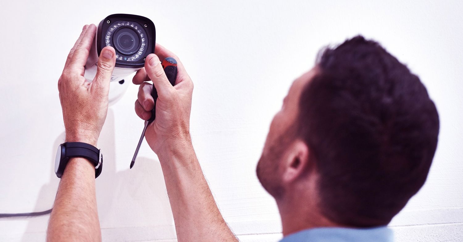 En man monterar en kamera på en vägg.