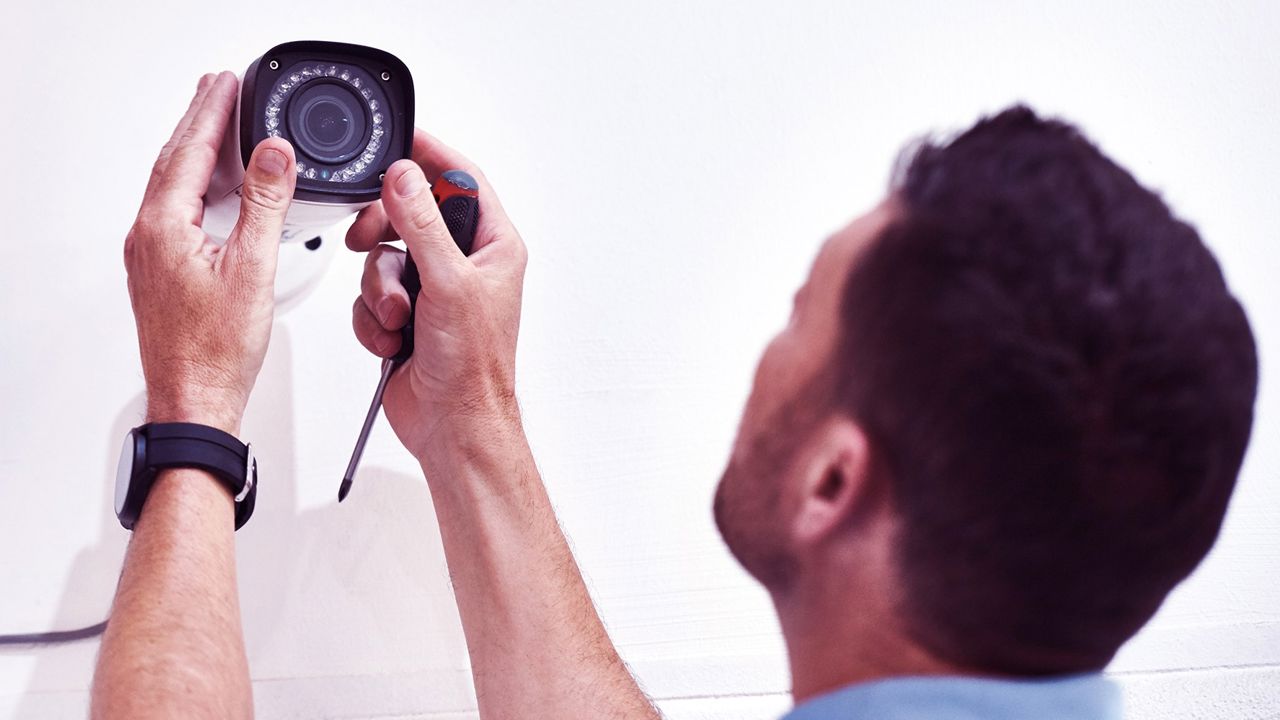 En man monterar en kamera på en vägg.